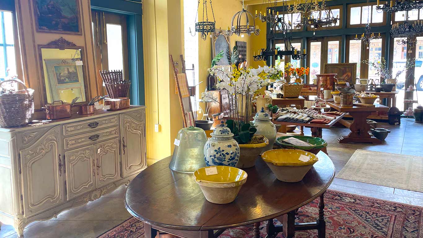 interior of aubergine antiques in fairhope alabama with dining table, buffets, mirrors and decorative accessories